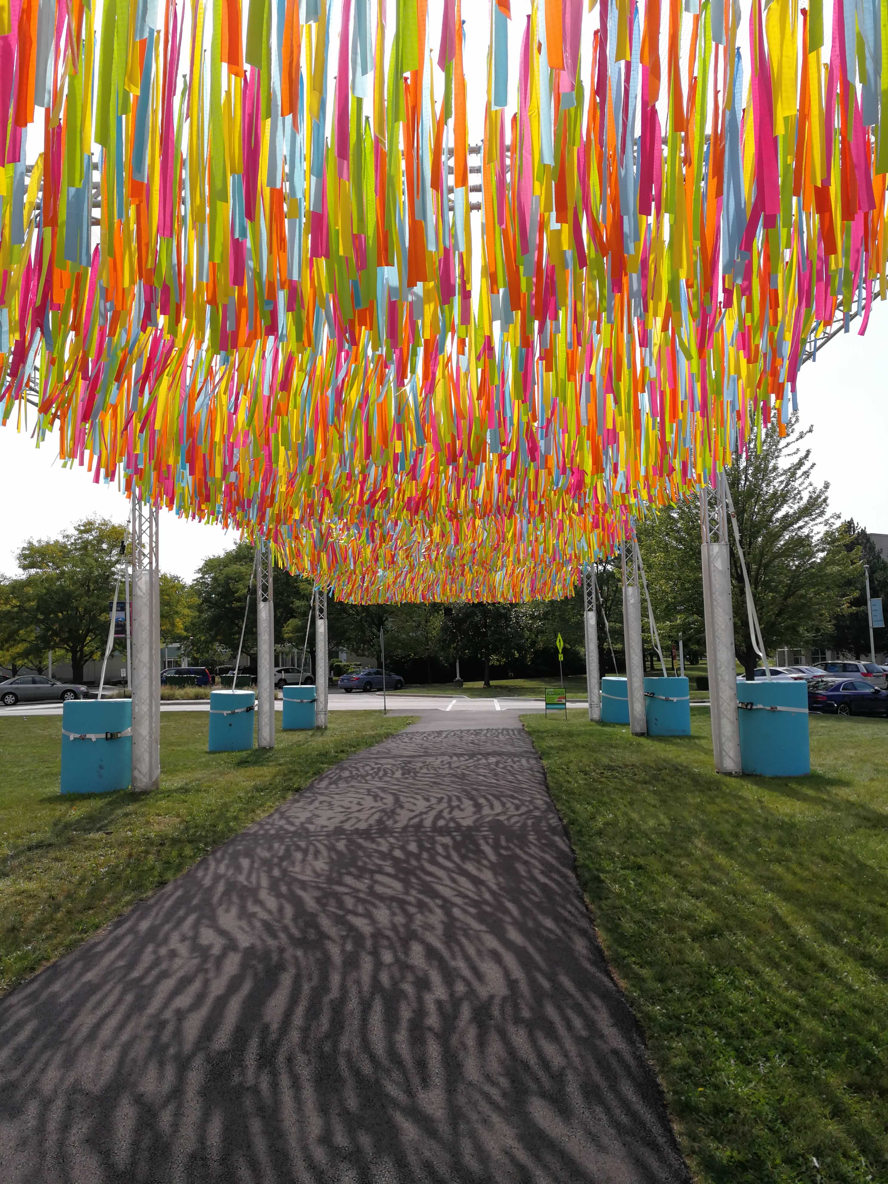 Bright yellow, green, blue, orange, and magenta streamers sit suspended above the walkway, casting stark shadows.